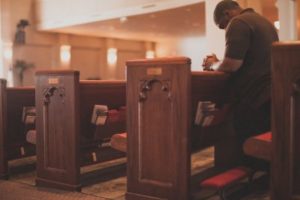 man praying in church pew