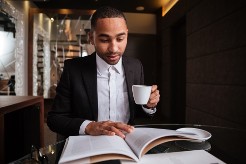 man reading bible drinking coffee