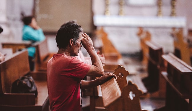 man praying in church sanctuary