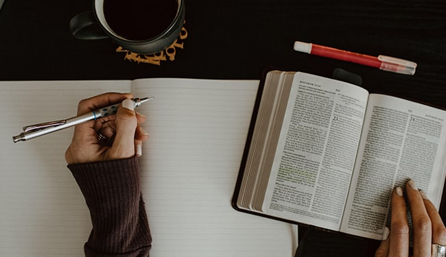 woman taking notes from bible