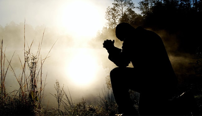 man praying at lake