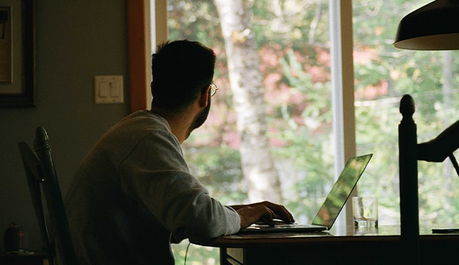 man working on laptop looking outside
