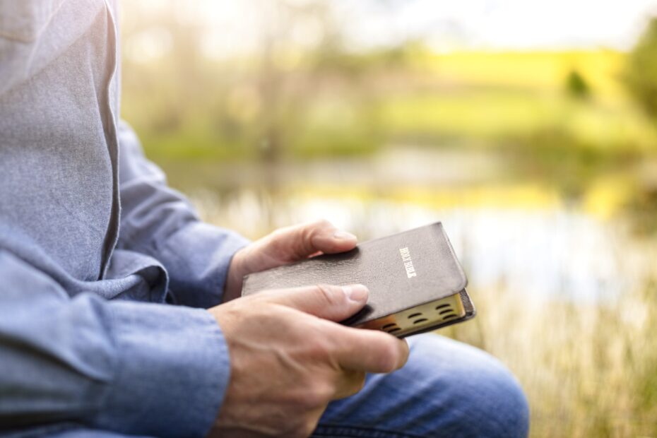 man holding bible while kneeling down