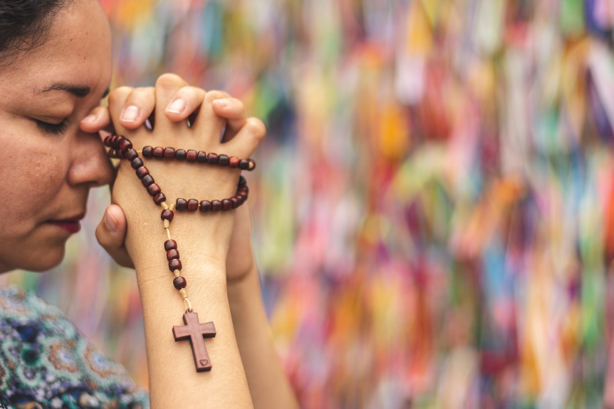 hispanic woman praying with rosary