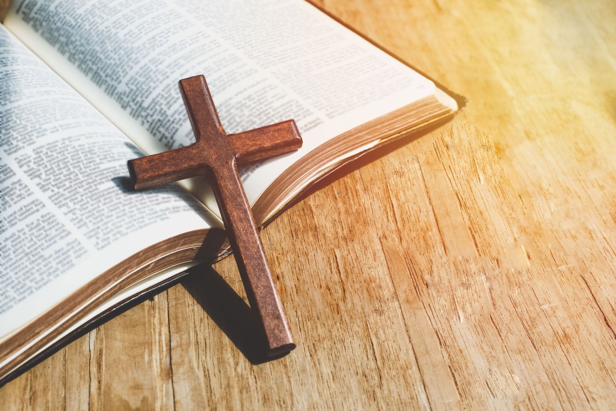 wooden cross laying on top of open bible