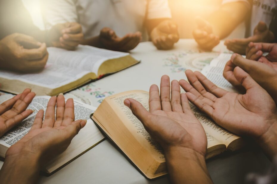 small group holding out hands and reading bibles