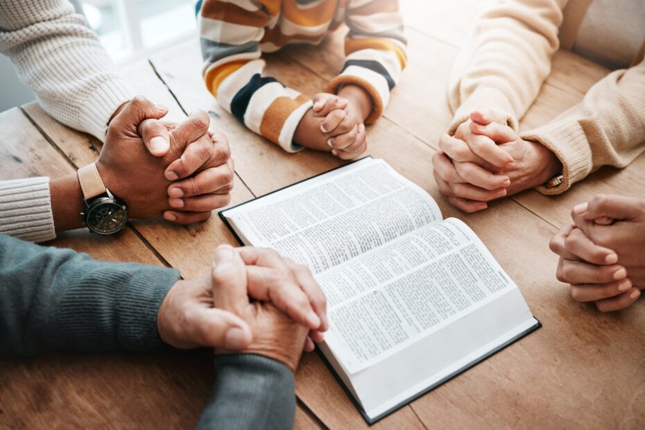 people of multiple ages praying next to open bible