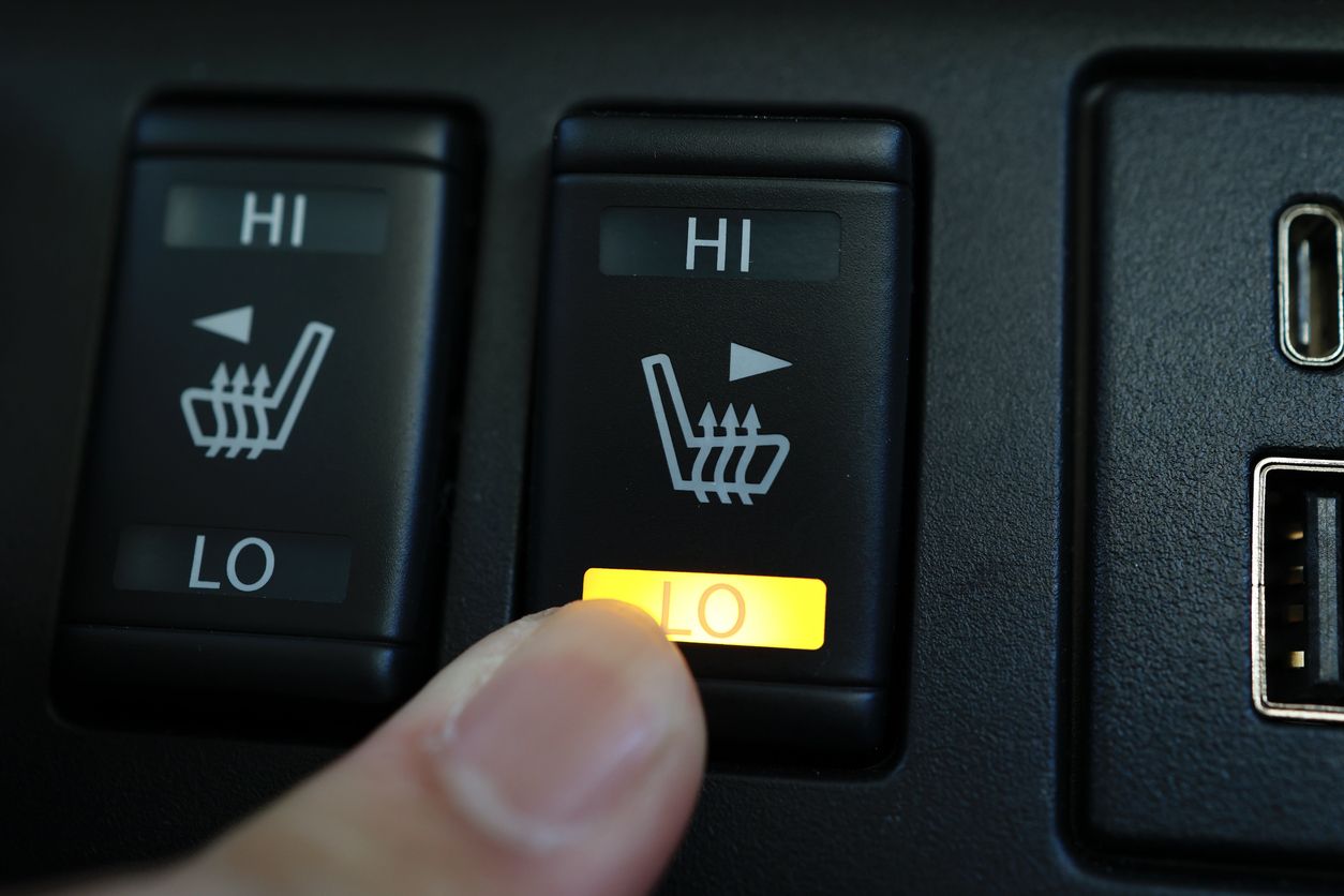 A seated heat button being pushed in a car